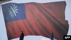 人们走过台湾新北市为竞选集会竖立起的一面台湾旗帜画像。(2024年1月12日)