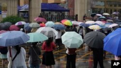 资料照片:家长和老师们冒雨在北京一所学校外等候正在参加一年一度的全国高考的考生们。(2024年6月7日)