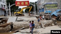 中国河北涿州一名男子抱着女儿试图穿过被洪水冲垮的桥。(2023年8月7日)