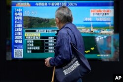 台湾强震后,东京一名男子驻足观看日本一家电视台播放对冲绳地区的海啸警报。(2024年4月3日)