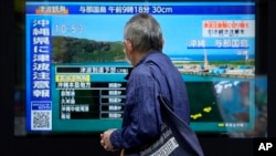 台湾强震后,东京一名男子驻足观看日本一家电视台播放对冲绳地区的海啸警报。(2024年4月3日)