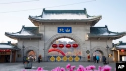 资料照片:2020年1月23日,游客们走过中国吉林省吉林市北山公园的大门。(美联社照片)