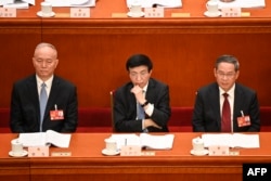 资料照:左起:中共中央政治局常委蔡奇、王沪宁(左)与李强在人大会堂出席全国人大会议。(2023年3月7日)