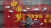 资料照:一名戴着口罩的男子在武汉街头一个中国梦的政府宣传牌下打盹。(2020年4月8日)