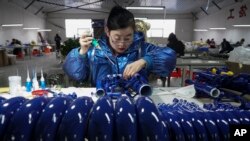 中国河北武强县的一名乐器厂工人在生产线上。(2023年2月23日)