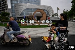 中国西安市民路过街头竖立的中亚峰会宣传牌。(2023年5月17日)