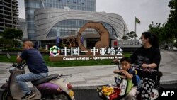 中国西安市民路过街头竖立的中亚峰会宣传牌。(法新社2023年5月17日)