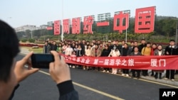 中国福建厦门竖立起一个台湾金门岛可以看到的“一国两制统一中国”的大型标语牌,旅游者在前拍照。(2024年1月12日)