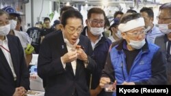 日本首相岸田文雄在东京一个水产品市场时食用福岛附近水域打捞的海鲜。(2023年8月31日)