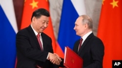 2023 年 3 月 21 日,俄罗斯莫斯科克里姆林宫,俄罗斯总统弗拉基米尔·普京(右)和中国国家主席习近平在会谈后的签字仪式上握手交换文件。
