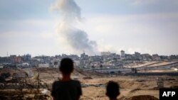 Rafah ဒေသတိုက်ပွဲတွေကြောင့်ထွက်လာတဲ့မီးခိုးလုံးတွေကို စစ်ဘေးရှောင်ကလေးနှစ်ဦး ဘေးလွတ်ရာက ကြည့်ရှုနေစဉ် (မေ ၁၃၊ ၂၀၂၄)