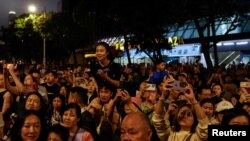 游客们在香港维多利亚港观看五一节的烟花。(2024年5月1日)