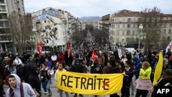 抗议民众在法国南部马赛市沿圣查尔斯火车站拾级而上,队伍前面的黄色横幅上的法文“RETRAITE”意思是“退休”,但是该法文词中最后一个字母“E”被打上红X,去掉了“E”这个词的意思就变成”取消“或”去除“。法国民众用讽刺的方法对马克龙政府的延迟退休计划表达反对和抗议。