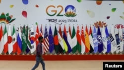 2023年9月8日,新德里G20峰会前,一名男子在会员国国旗前走过。