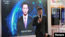 在中国浙江嘉兴乌镇举办的第五届世界互联网大会(WIC)博期间,新华社新闻主播邱浩在搜狗展台上站在以他为原型的人工智能虚拟新闻主播旁边。(资料照片,2018年11月7日)