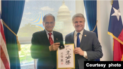 台湾立法院院长游锡堃(左)与美国国会众议院外交事务委员会主席麦考尔众议员会面时,致赠他自己的手写书法“民主必胜”。(2023年5月17日,麦考尔众议员办公室提供)