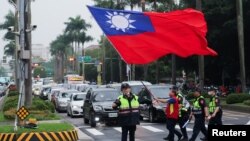 台湾警察护送一名举着台湾旗帜的男子走过台北街头。(2024年5月24日)