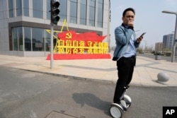 中国河北雄安街头一名男子路过一处口号宣传牌。(2023年4月1日)