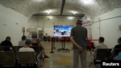 中国浙江省杭州市遭热浪袭击,居民在防空洞里避暑时看巴黎奥运会比赛。(2024年8月2日)