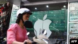 资料照:一名越南女子在河内骑电动车路过一家苹果专卖店。(2012年9月28日)