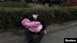 北京一家儿童医院外一名男子怀抱一个幼童。(2023年11月27日)