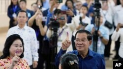 2023 年 7 月 23 日,柬埔寨首相洪森(右)与妻子文·拉尼(左)在柬埔寨金边东南部塔克穆阿的一个投票站投票后,展示了沾有墨水的手指。