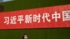 一名女子从北京街头张贴的一条宣传习近平新时代的标语下走过。(2019年9月27日)