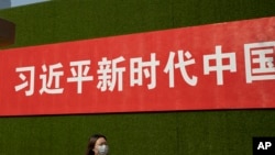 一名女子从北京街头张贴的一条宣传习近平新时代的标语下走过。(2019年9月27日)