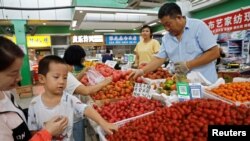 北京一家早市的顾客在挑捡西红柿。(2023年8月9日)