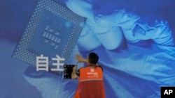 资料照:一名工人在上海举办的世界人工智能大会上检查中国科技公司中科曙光展示的芯片与自主字样的屏幕。(2023年7月5日)