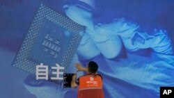 一名工人在上海举办的世界人工智能大会上检查中国科技公司中科曙光展示的芯片和自主字样的屏幕。(2023年7月5日)