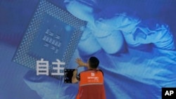 资料照片:一名工人在上海举办的世界人工智能大会上检查中国科技公司中科曙光展示的芯片和自主字样的屏幕。(2023年7月5日)