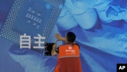 一名工人在上海举办的世界人工智能大会上检查中国科技公司中科曙光展示的芯片和自主字样的屏幕。(2023年7月5日)