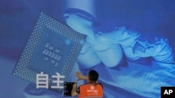 一名工人在上海举办的世界人工智能大会上检查中国科技公司中科曙光展示的芯片和“自主”
字样的屏幕。(2023年7月5日)
