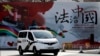 资料照:一辆警车驶过北京街头一堵宣传中国法治的宣传墙。(2016年12月28日)