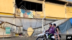 A motorcycle passes by a grocery store damaged by an earthquake in Bayugan City, southern Philippines, Dec. 3, 2023.