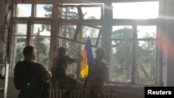 乌克兰士兵在反攻中夺下顿涅茨克地区的一个村庄后在一个建筑里插上乌克兰国旗。(2023年6月11日)