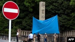 日本东京靖国神社入口处的石柱遭涂鸦,当局用一块蓝布遮挡。(2024年8月19日)