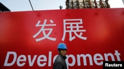 资料照:一名工人走过北京一处建筑工地的宣传标语。(2014年12月12日)