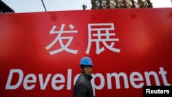 资料照:一名工人走过北京一处建筑工地的宣传标语。(2014年12月12日)