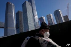 一名打工人扛着他的行李行走在北京商务区。(2023年3月15日)