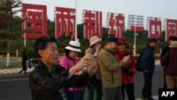 中国福建厦门竖立起一个台湾金门岛可以看到的“一国两制统一中国”的大型标语牌,旅游者在前拍照。(2024年1月12日)