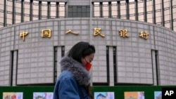 资料照片:一名女子走过位于北京的中国人民银行。(2024年2月20日)