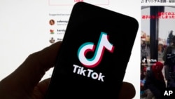 资料图片:在一台显示TikTok主屏幕的电脑前,人们看到手机上的 TikTok徽标。(波士顿,2023年3月 18日,波士顿)