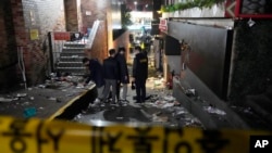 2022年10月30日,在韩国首尔,一群主要是年轻人的人在庆祝万圣节时涌入一条狭窄的小巷,被困和踩踏,警察正在检查伤亡事故的现场。