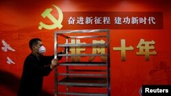 一名工作人员在北京一家酒店的中共二十大新闻中心走过宣传中国领导人习近平的标语。(2022年10月19日)
