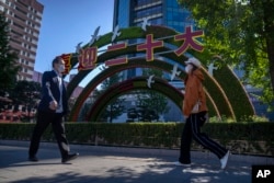 行人走过北京街头竖立的迎接中共二十大的宣传牌。(2022年10月11日)