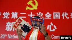 资料照:一名记者在北京一家酒店的中共二十大新闻中心阅读有着中国领导人习近平照片封面的杂志。(2022年10月19日)