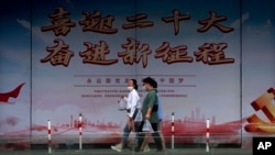 行人走过北京街头竖立的中共二十大宣传牌。(2022年8月17日)