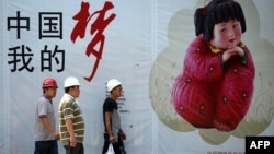 资料照:几名中国工人走过北京街头张贴的中国梦宣传画。(2013年9月2日)